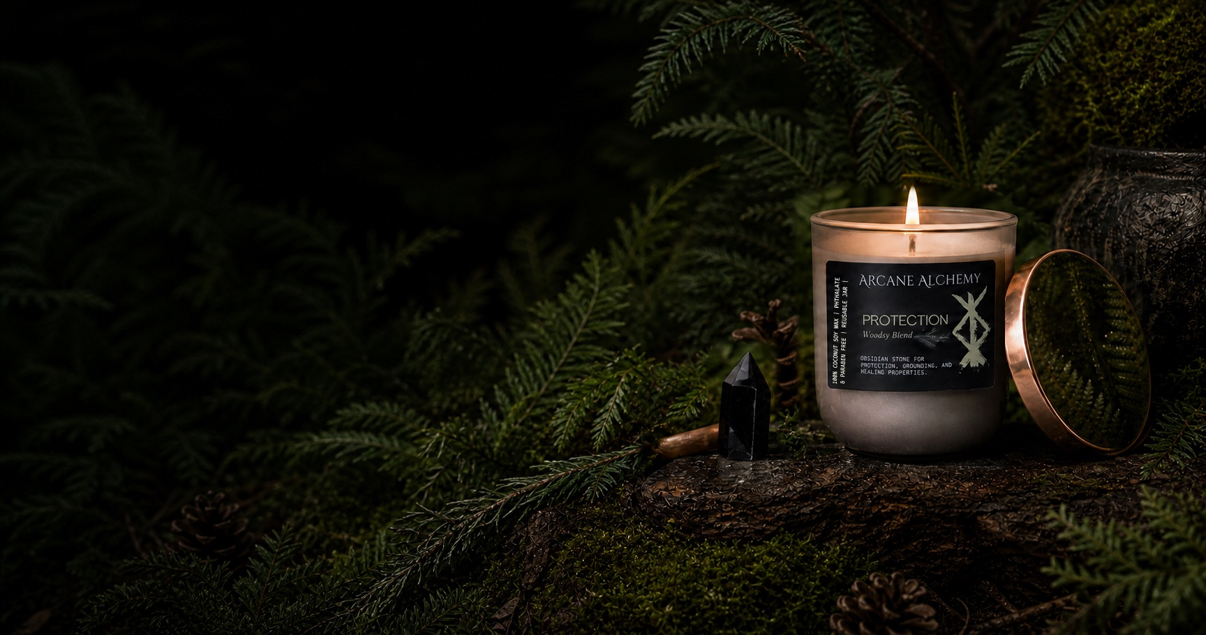 Arcane Alchemy Woodsy Protection candle in smoky glass with its reflective copper lid, black obsidian and evergreen forest botanicals